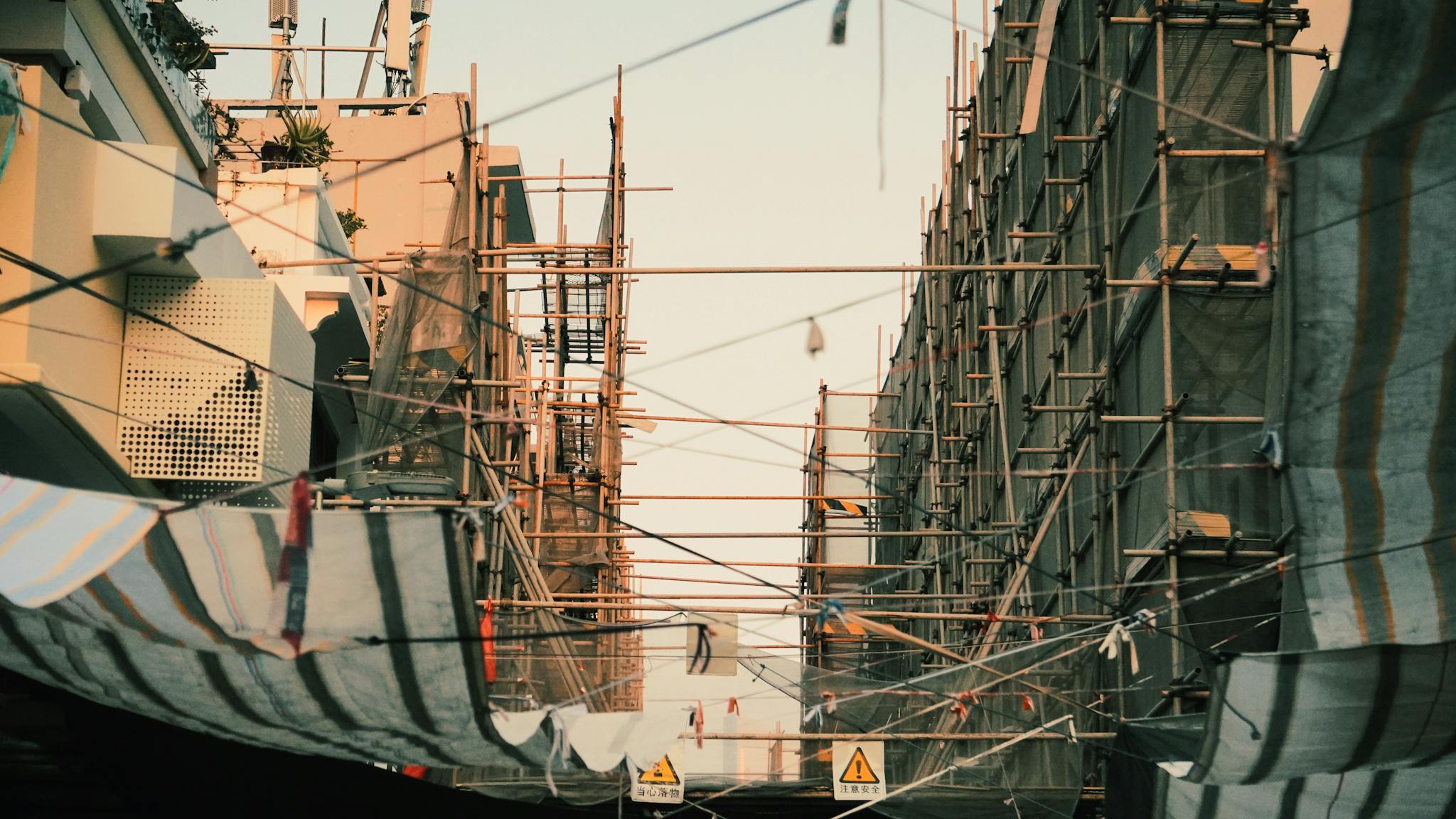 Construction scaffolding in a city with a sunset backdrop creates a striking urban atmosphere.